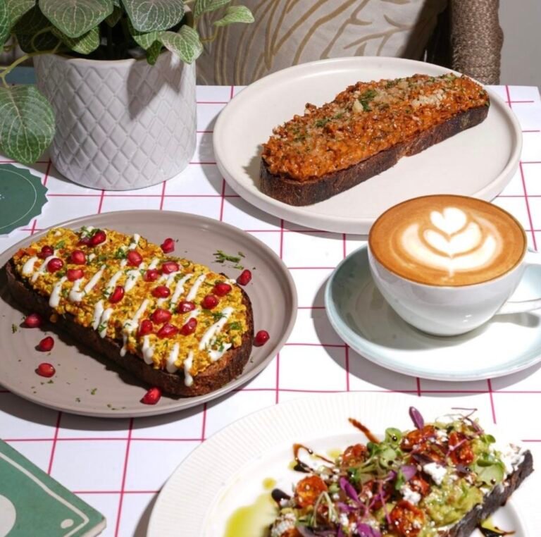 Toasts with toppings and a cup of coffee on a table.