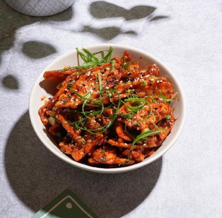 Bowl of spicy stir-fried vegetables garnished with herbs.
